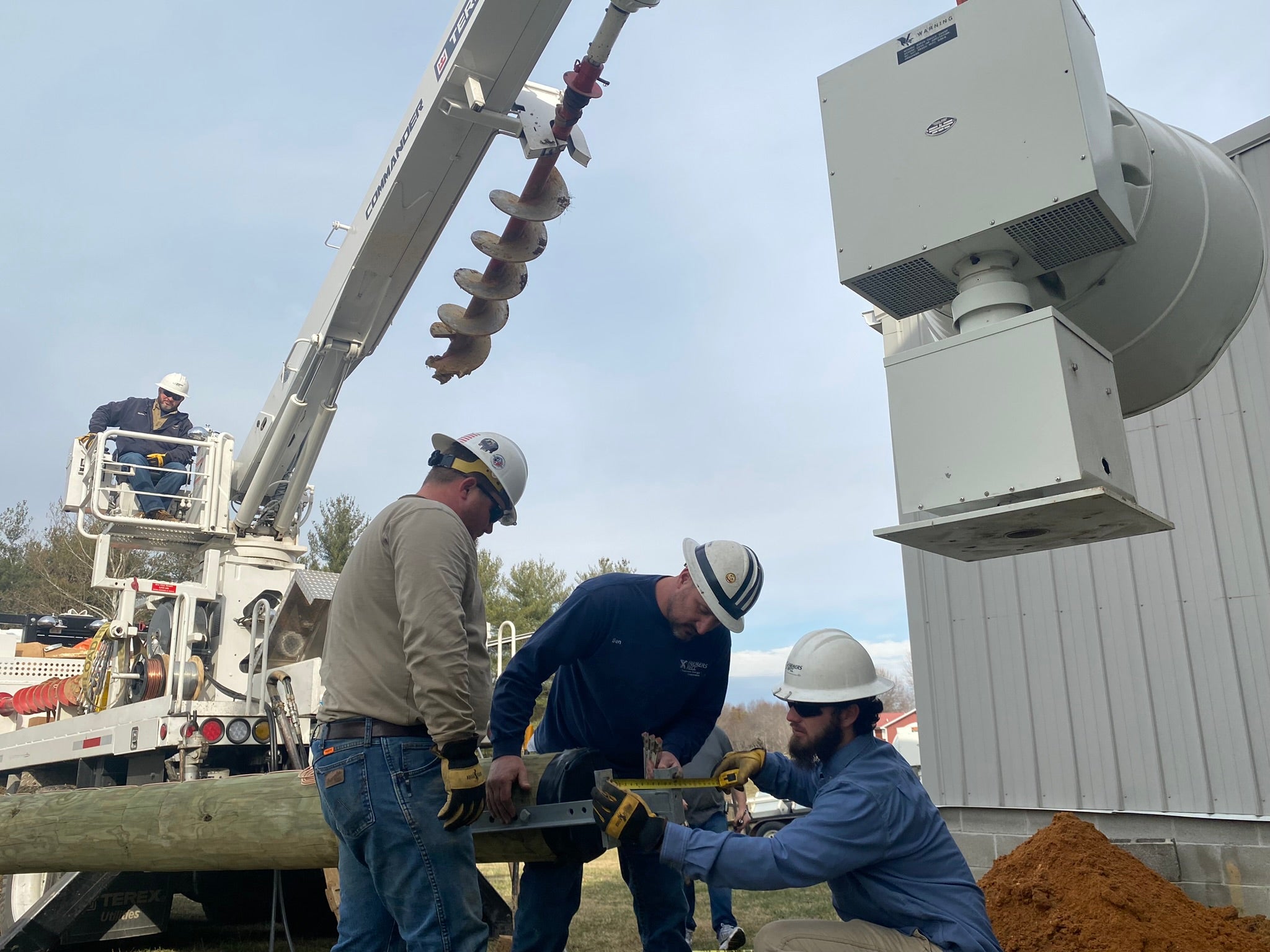 Farmers RECC employees set a pole in the field